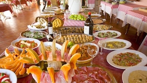 A buffet table with various dishes, including meats, cheeses, and salads, set up in a dining area with tables covered in tablecloths. - Agrihotel Elisabetta (Cecina)