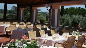 An outdoor dining area with tables set for guests, surrounded by wicker chairs and covered with white tablecloths. - Agrihotel Elisabetta (Cecina)