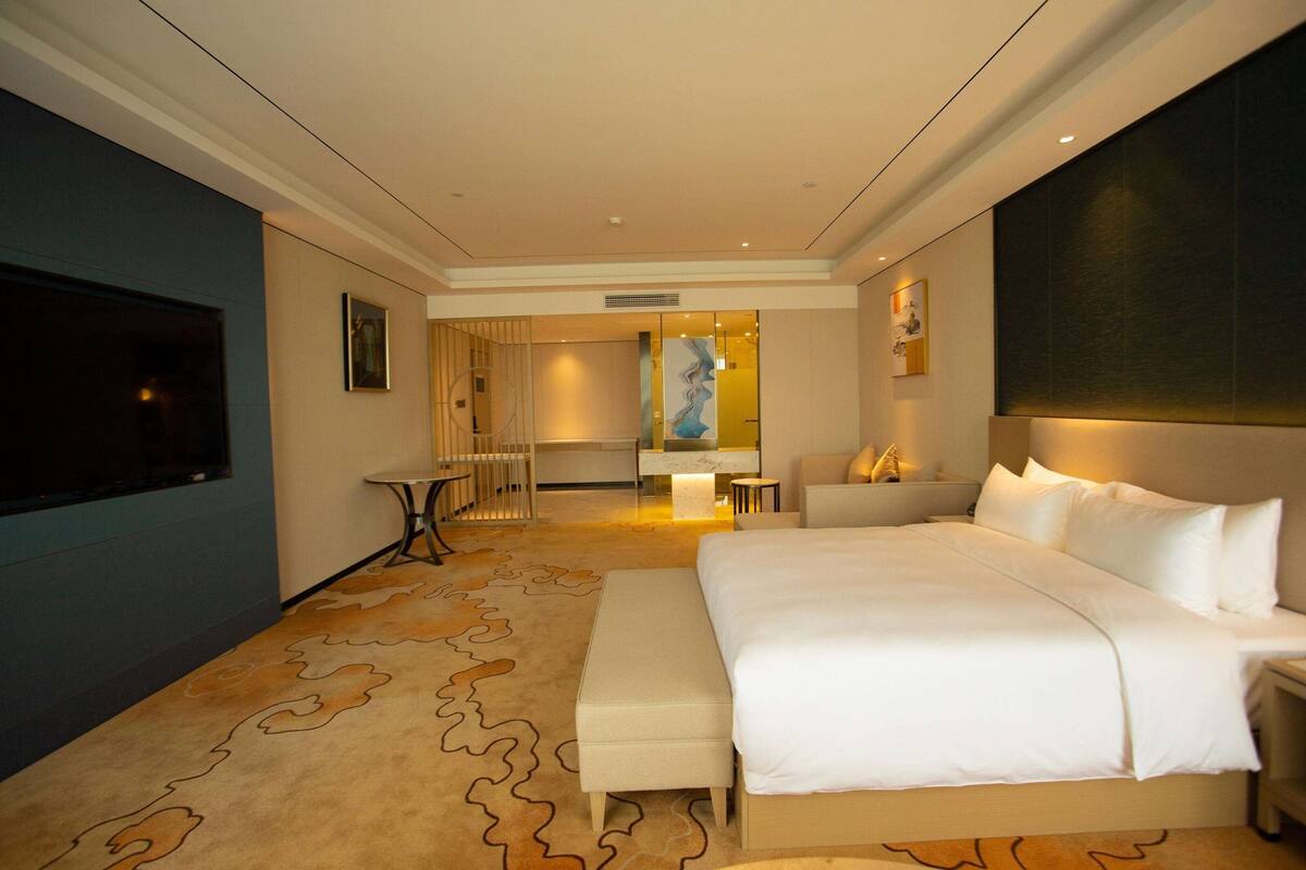 Una habitación de hotel moderna con una cama grande, un televisor de pantalla plana, un escritorio y una zona de estar.