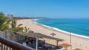 A beachside view with a bar area featuring outdoor seating and a thatched roof. - Oceanfront  Condo at Costa Azul Beach ! (San José del Cabo)