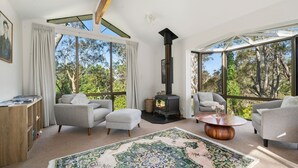 Una sala de estar moderna con un ventanal grande, una chimenea y una zona de estar acogedora.
