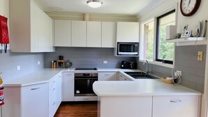 Una cocina moderna con armarios blancos, horno integrado, microondas y pileta.