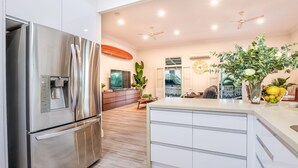 A modern kitchen with a stainless steel refrigerator, wooden flooring, and a central island with a sink. - WESTACOMBE -  boat parking plus amazing pool, pet friendly (AGNES WATER)
