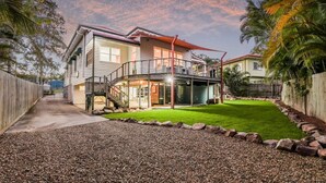 A two-story house with a balcony, a covered patio, and a well-maintained lawn. - WESTACOMBE -  boat parking plus amazing pool, pet friendly (AGNES WATER)