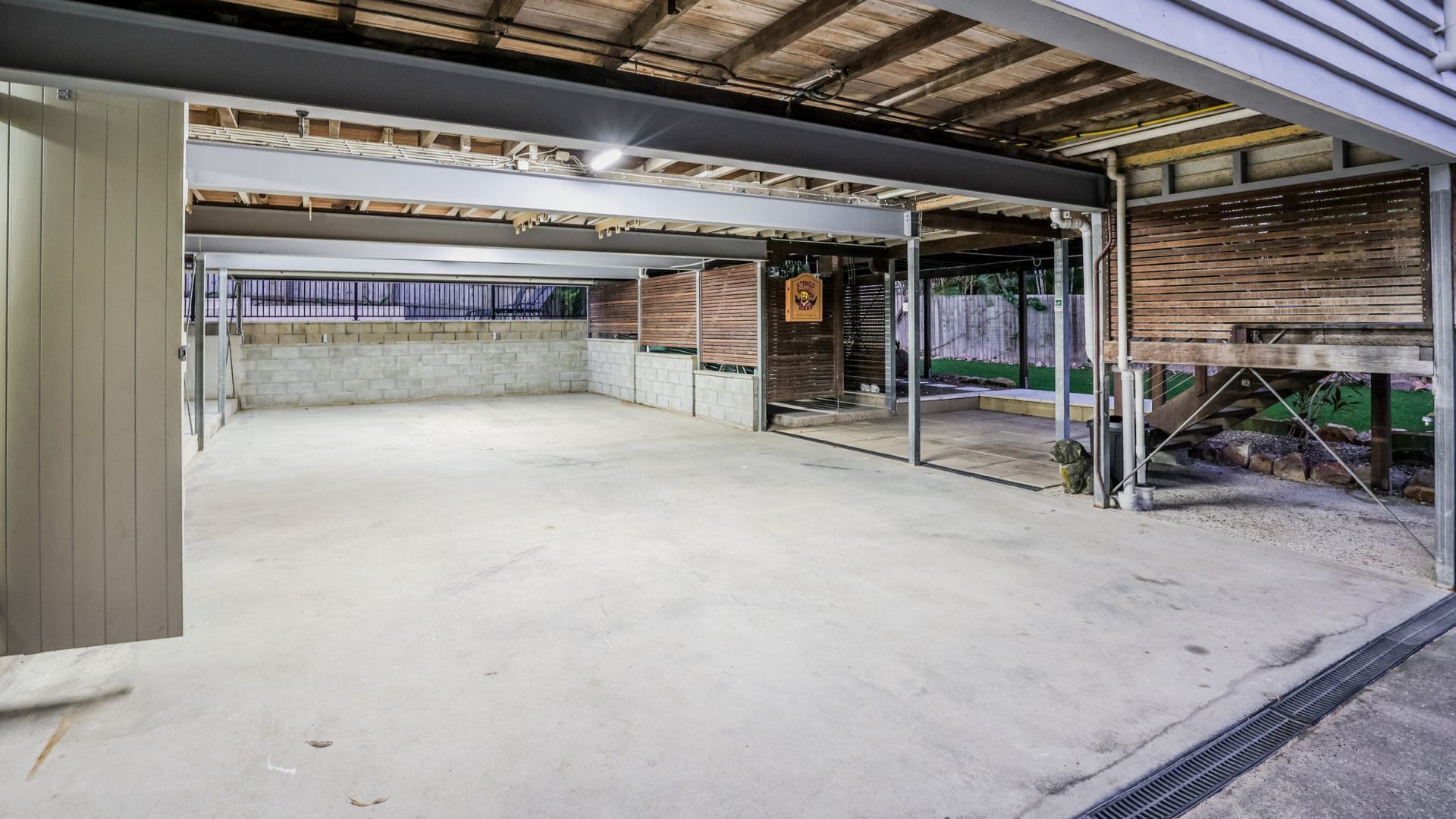 A spacious indoor area with a concrete floor, metal railings, and a wooden structure on the right.