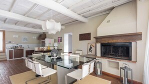 Una cocina moderna con una mesa de vidrio, sillas blancas y una chimenea de piedra.