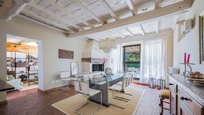 Un salón amplio con una mesa de comedor de vidrio, sillas modernas y una chimenea.