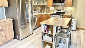 A modern kitchen with stainless steel appliances, wooden cabinets, and a central island with bar stools.