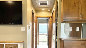 A hallway with wooden cabinets, a flat-screen TV, and a built-in refrigerator.