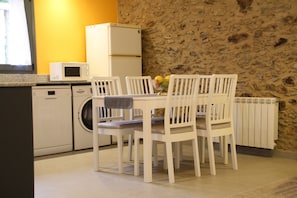 Una cocina compacta con lavadora, microondas y una mesa de comedor con sillas.