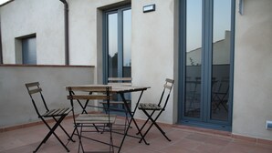 An outdoor patio with a wooden table and four chairs, a sliding glass door, and a small window. - House with two terraces (espolla)