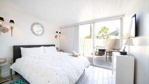Een hotelkamer met een groot bed, een bureau, een stoel, een televisie en een schuifdeur naar buiten.