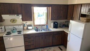 Une cuisine avec des meubles de rangement en bois, une cuisinière blanche, un évier et un réfrigérateur.