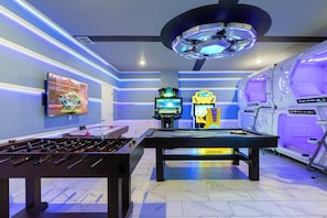 A room with a pool table, foosball table, arcade machines, and a large ceiling fan. - Ultimate Lakeview Villa with Everything! (Kissimmee)