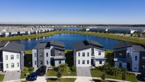 A residential area with modern houses, a central water feature, and a clear sky. - Ultimate Lakeview Villa with Everything! (Kissimmee)