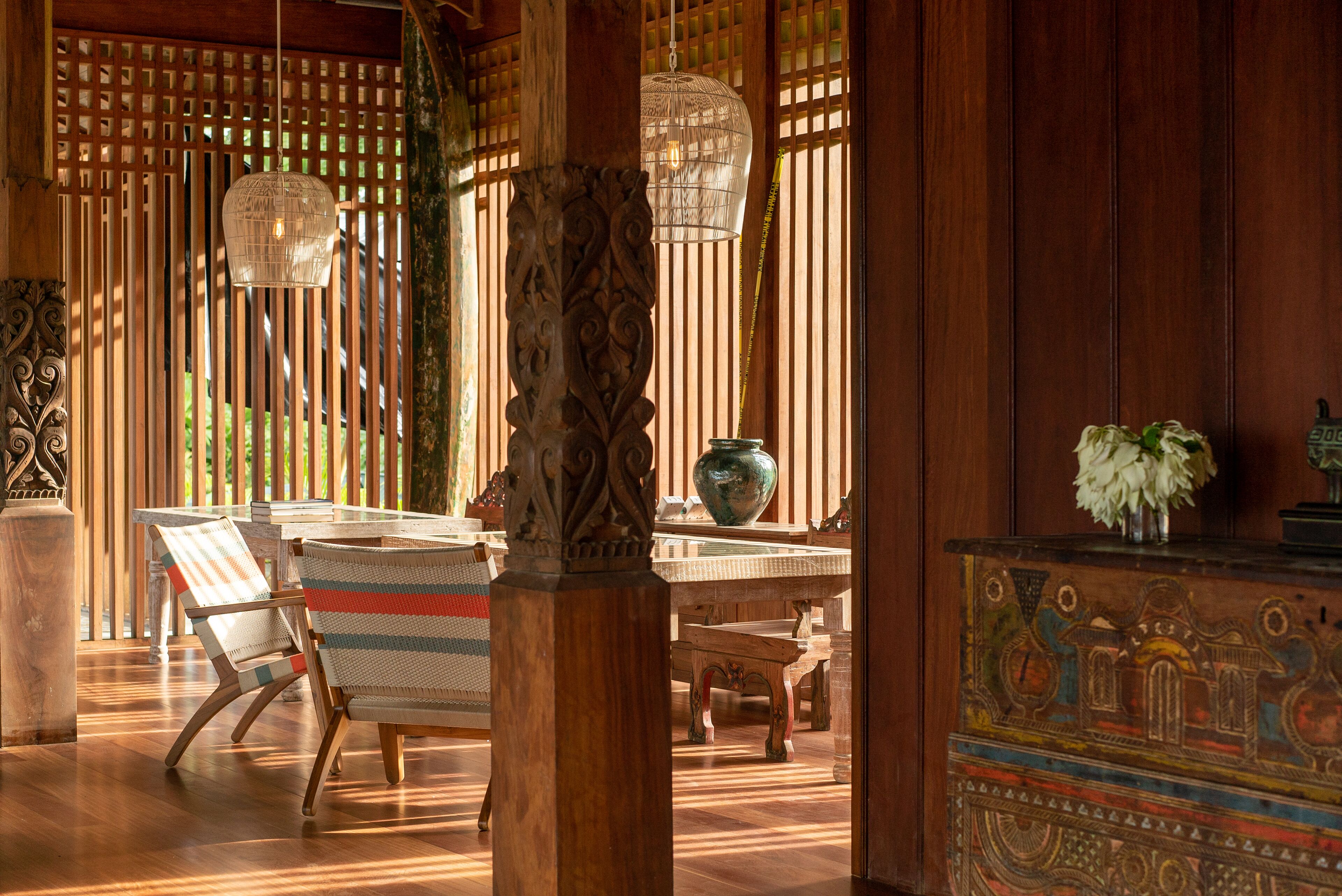 Un intérieur traditionnel en bois comprenant un coin repas avec une table et des chaises, un vase décoratif et un luminaire suspendu.