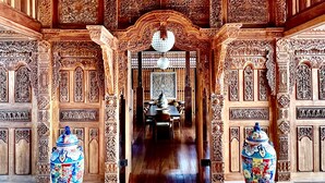 Un interior ornamentado con techo de madera, tallas intrincadas y un candelabro.