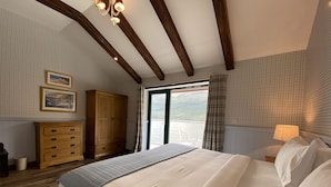 Un dormitorio con una cama grande, un armario de madera y vistas a un lago a través de un ventanal.