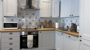 Una cocina moderna con armarios blancos, un microondas, una estufa y un lavabo.