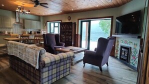 Un salon confortable avec un canapé, des fauteuils, une cheminée et un téléviseur.