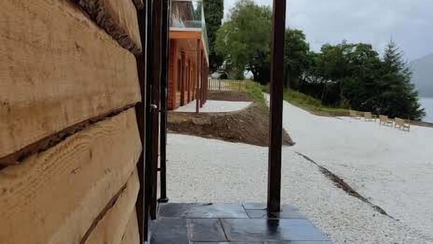 Un mur extérieur en bois, avec une entrée revêtue de pierres menant à un espace extérieur abrité.