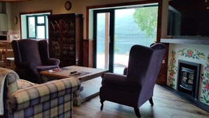 Un salon doté d’une cheminée, d’un téléviseur et offrant une vue sur l’extérieur.