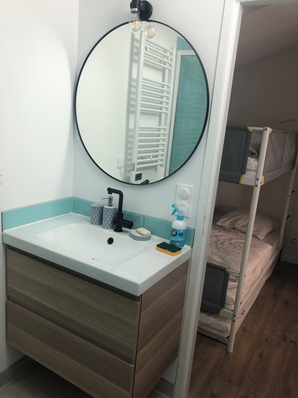 A bathroom with a round mirror, sink, and a towel rack. - Loft 90m2, terraces 90m2 (Lacanau)
