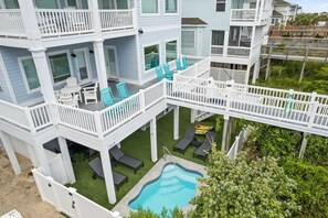 A multi-story building with balconies, a swimming pool, and outdoor seating. - License to Chill by Brunswick Vacation Rentals: 6BR Oceanfront w Elevator & Pool (Ocean Isle Beach)
