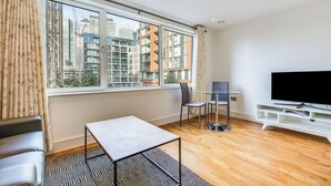 A modern living room with a large window, a TV, a small table, and a sofa.