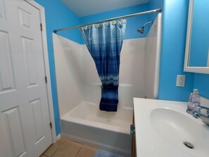 A bathroom with a bathtub, a shower, a sink, and a door. - Blue Bird Hill with Deck & Middle of Branson Location (Branson)