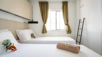 Ein Hotelzimmer mit zwei Betten, einem Fenster mit Vorhängen, einem Handtuch mit Logo und einer an der Wand stehenden Leiter.