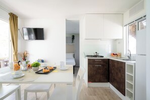 A modern kitchen with white cabinets, a built-in stove, and a window.