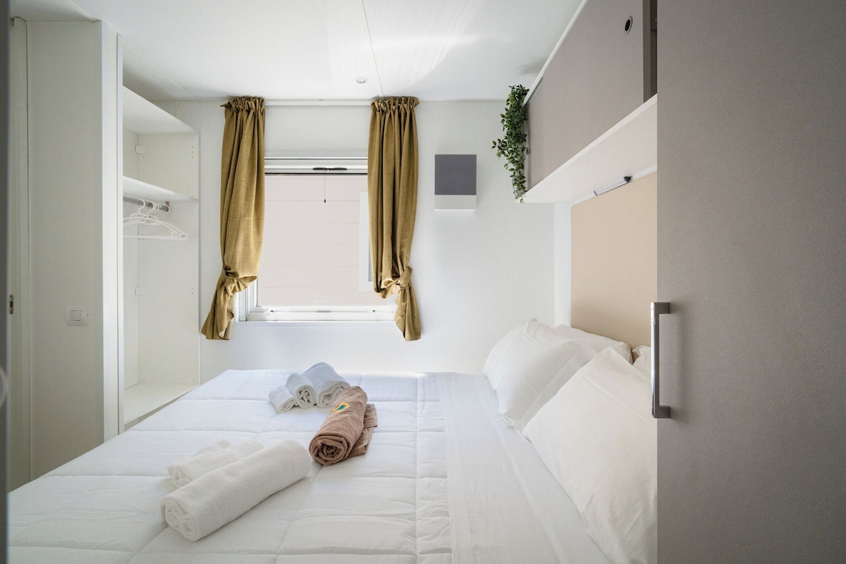 A hotel room with a bed, a wardrobe, and a window with curtains.