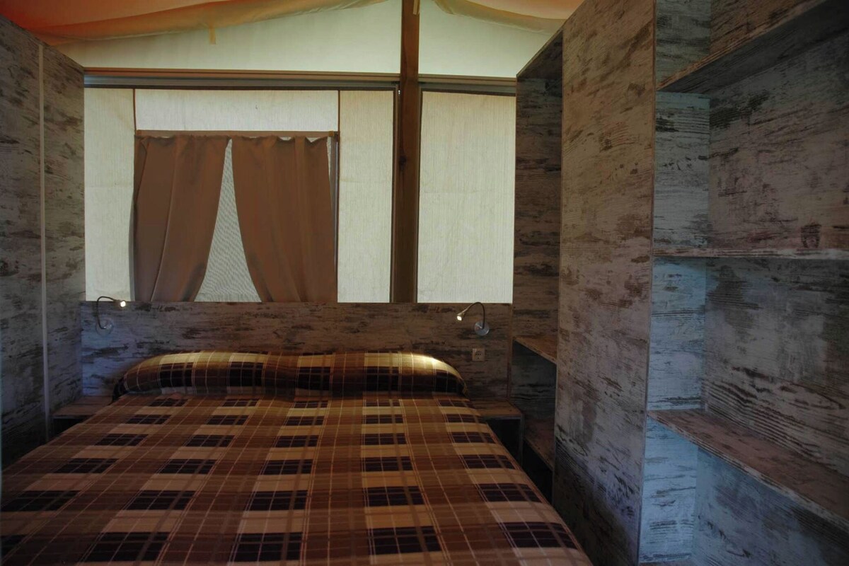 A bedroom with a bed, curtains, and a window.