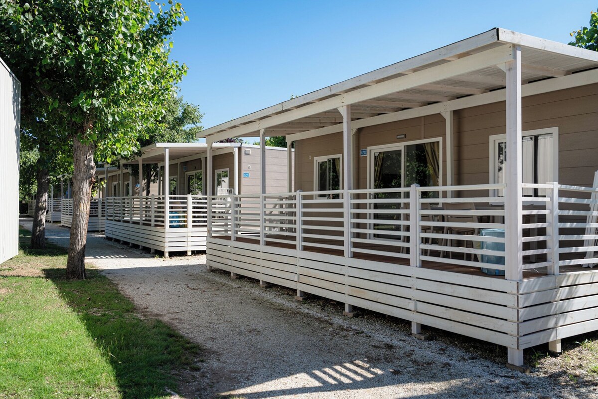 A row of single-story cabins with white railings and a covered walkway.