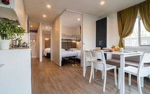 A compact hotel room with a kitchenette, a dining area, and a bed.