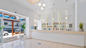 A clean, modern lobby with a reception desk, glass display shelves, and a view of parked cars outside. - Santa Maria City Hotel (Rhodes)