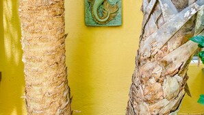 Un palmier et un mur orné d’une sculpture représentant une sirène.
