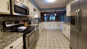 A modern kitchen with stainless steel appliances, white cabinets, and a tiled floor. - Solace Space at Foothills - Close To All Of Branson - Luxury Comfort (Branson)