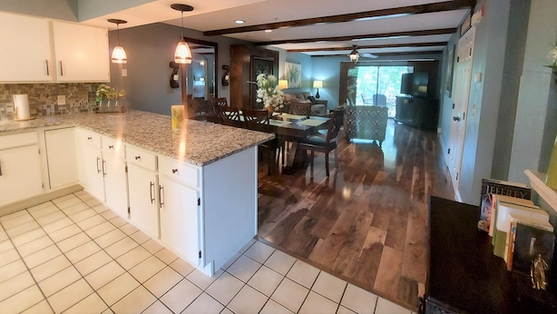 A modern kitchen with a large island, wooden flooring, and a dining area with a view of the outdoors. - Solace Space at Foothills - Close To All Of Branson - Luxury Comfort (Branson)