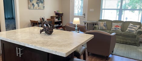 A kitchen with a marble countertop, a wooden island, and a dining area with chairs and a table.