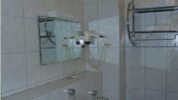 A bathroom with a mirror, a towel rack, and a sink. - Hotel Domino (Hanau)