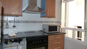 A kitchen with a stove, microwave, and cabinets. - Suncanarias Apartamento Marina (San Miguel de Abona)