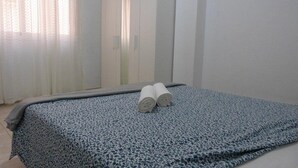 A bedroom with a bed, a wardrobe, and a window with curtains. - Suncanarias Apartamento Marina (San Miguel de Abona)
