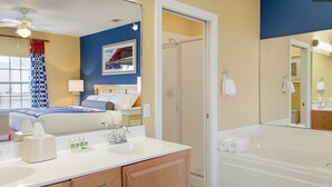 Habitación de hotel con cama, baño con bañera, lavamanos y espejo.
