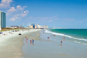 A beach with a Ferris wheel, buildings, and a clear sky. - Oceanfront Condo in Myrtle Beach! Pools, lazy river & lots of amenities! (Myrtle Beach)