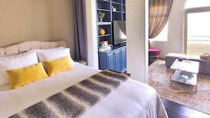 Habitación de hotel con una cama grande, televisión, estantería y vistas al exterior.