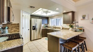 Una cocina moderna con una isla central, electrodomésticos de acero inoxidable y un ventanal que proporciona luz natural.
