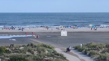 Una playa con gente relajándose y caminando por la orilla.