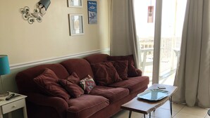 A living room with a red sofa, a small table, and a window with curtains.